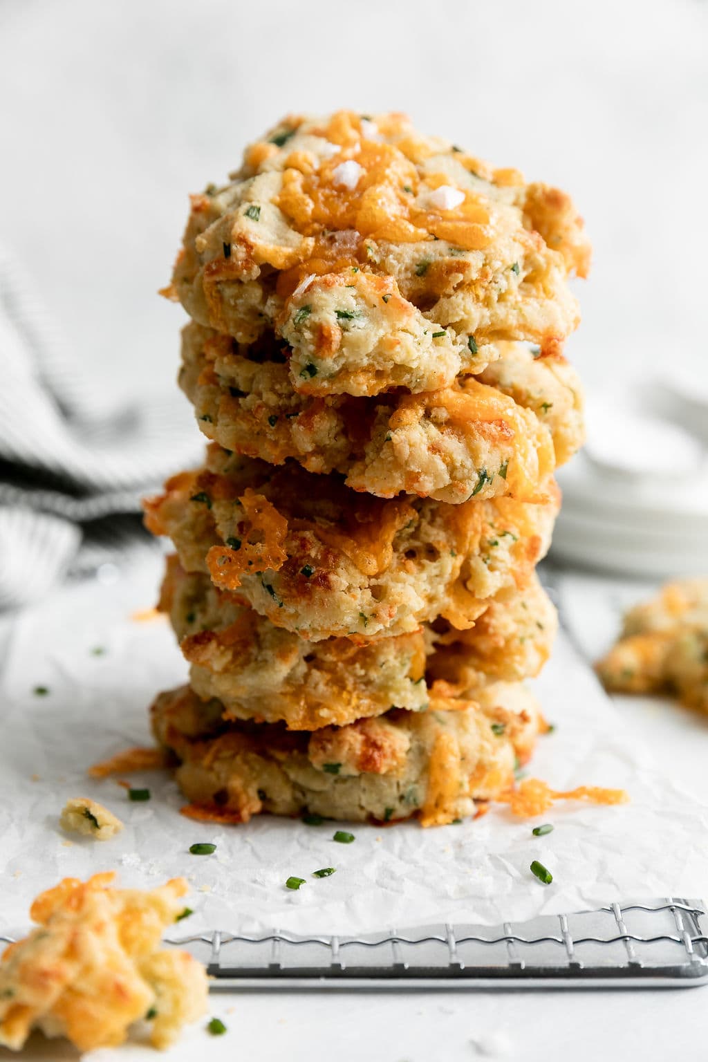 Garlic cheddar gluten free biscuits stacked on top of each other on a parchment-covered cooling rack.