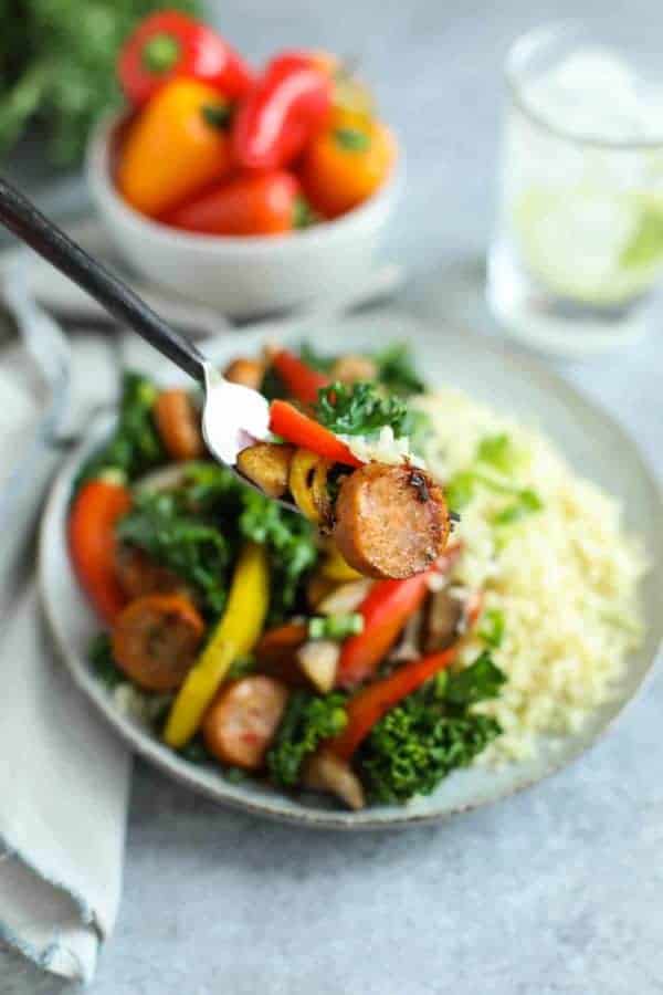 Forkful of Grilled Chicken Sausage and Veggies over Cauliflower Rice being raised to the camera.
