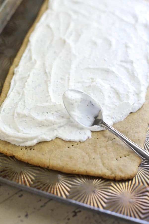 Sour cream being spread on a pizza crust