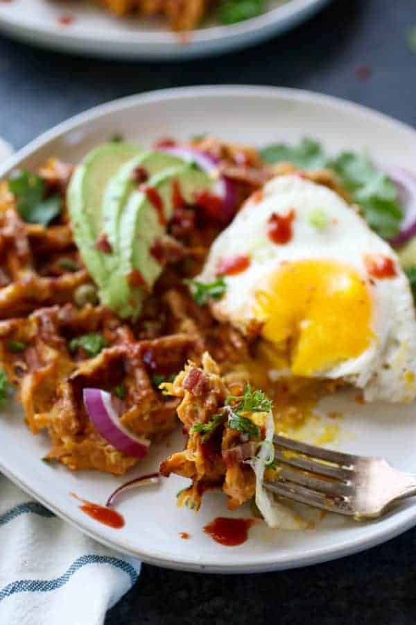 Savory Sweet Potato Bacon Waffles on a silver fork resting on a white plate