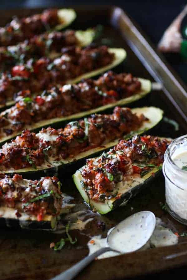 Italian-Sausage Stuffed Zucchini Boats on a sheet pan with one sliced down the middle