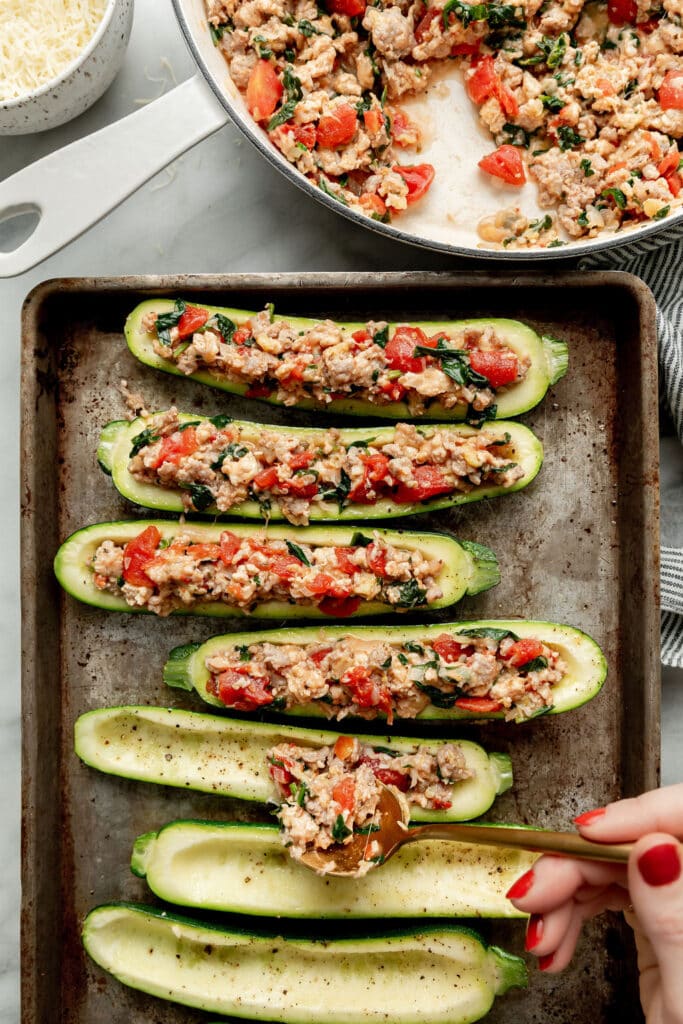 Overhead view of Italian-Sausage mixture being Stuffed into Zucchini Boats.