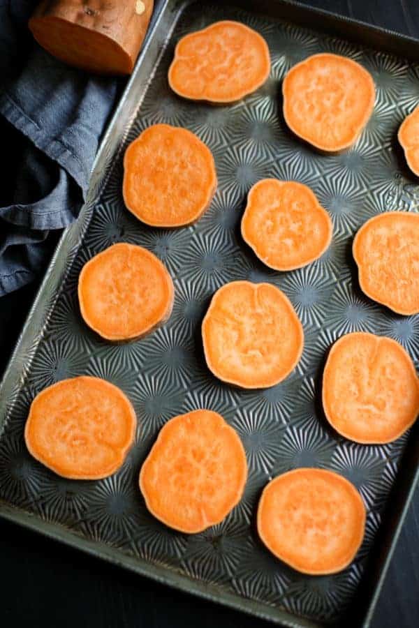 Sweet potato slices on a gray cooking sheet