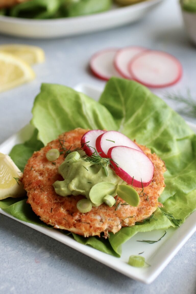 Salmon Burger on lettuce topped with avocado garlic sauce and sliced radish