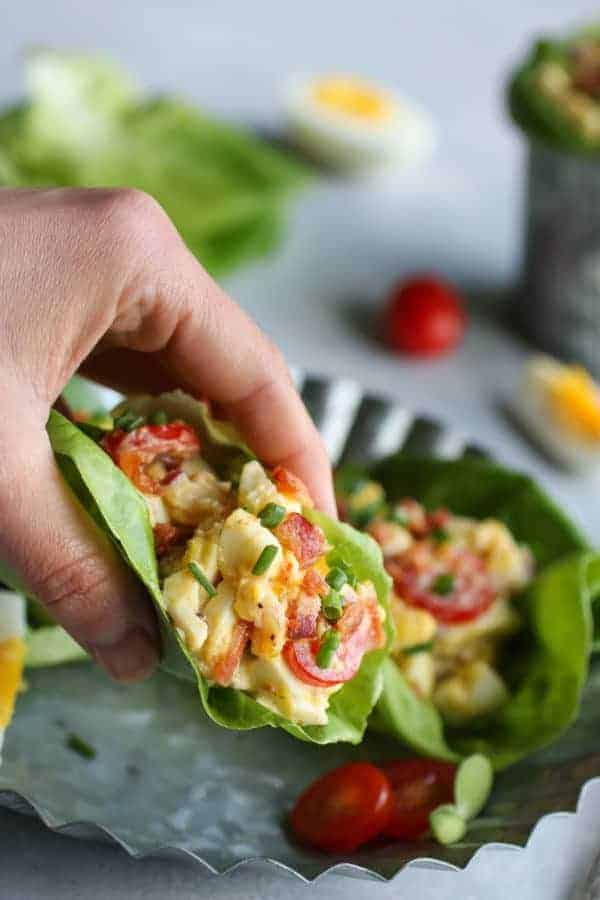 BLT Egg Salad in a lettuce wrap in a person's hand facing the camera