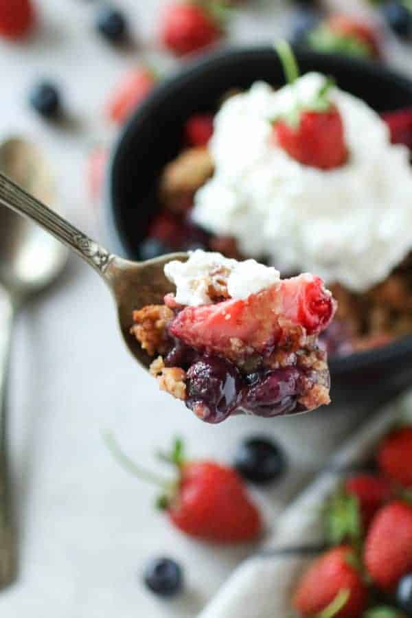 Grain-free berry crisp on a silver spoon facing the camera