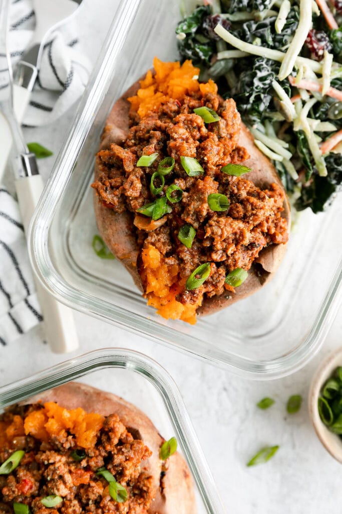 Sloppy joe stuffed sweet potato in meal prep container with side salad