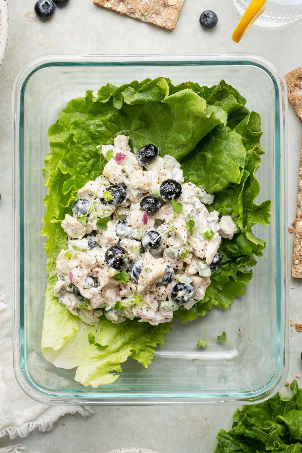 Overhead view of a glass meal prep container with Blueberry Chicken Salad on top of lettuce leaves.