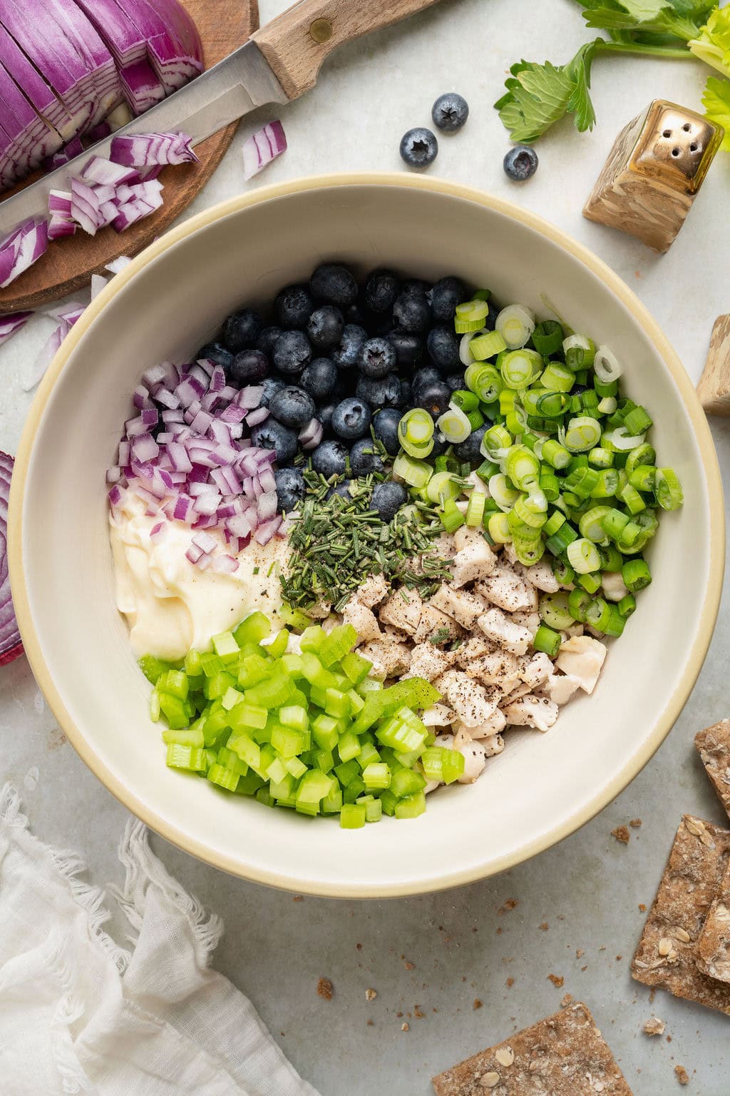 Overhead view of a white bowl filled with ingredients for Blueberry Chicken Salad arranged in sections.