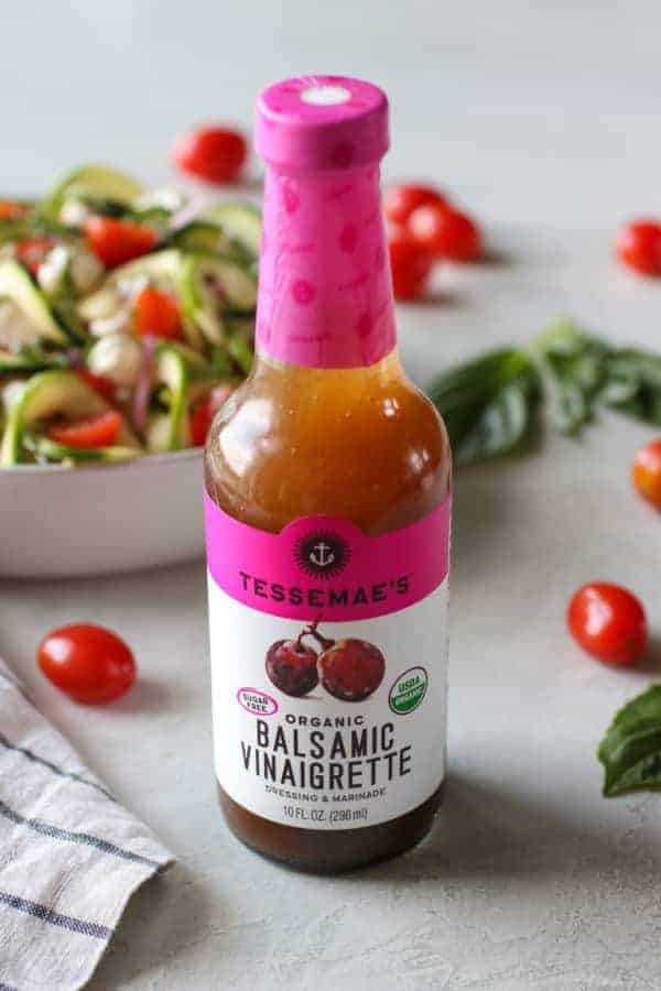 Tessemae's Organic Balsamic Vinaigrette bottle with the caprese salad in the background