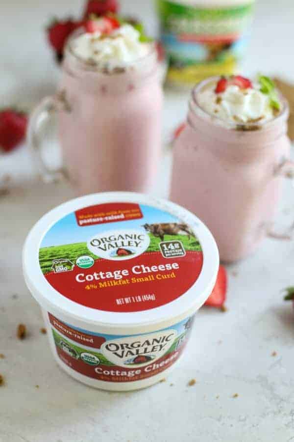 Organic Valley Cottage Cheese with two glasses of Strawberry Cheesecake Smoothies in the background