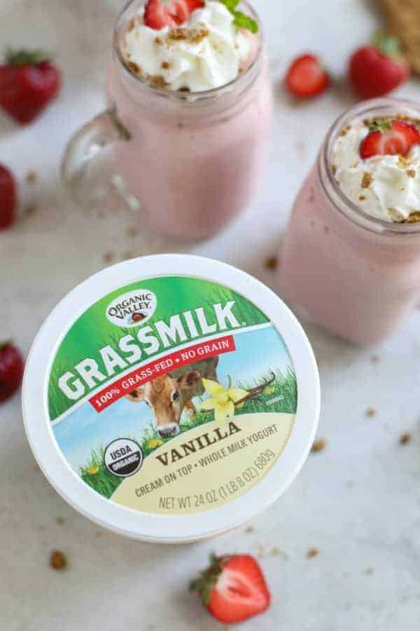 overhead view of Grassmilk Vanilla Whole Milk Yogurt with two glasses of Strawberry Cheesecake Smoothies