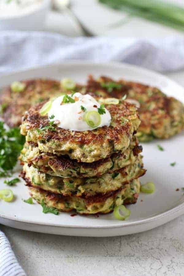 Savory Zucchini Fritters stacked on a white plate