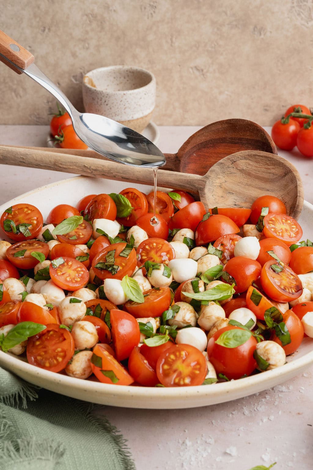 Olive oil being drizzled over a plate of caprese salad.
