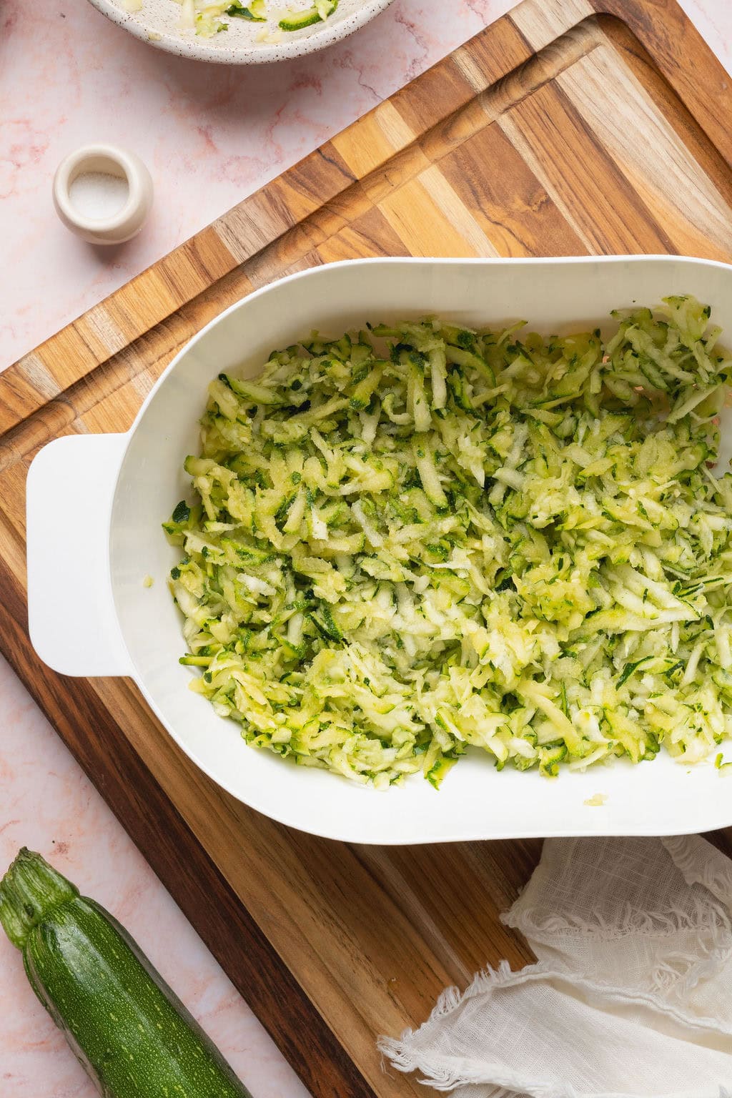Grated zucchini in the bottom of a casserole dish.