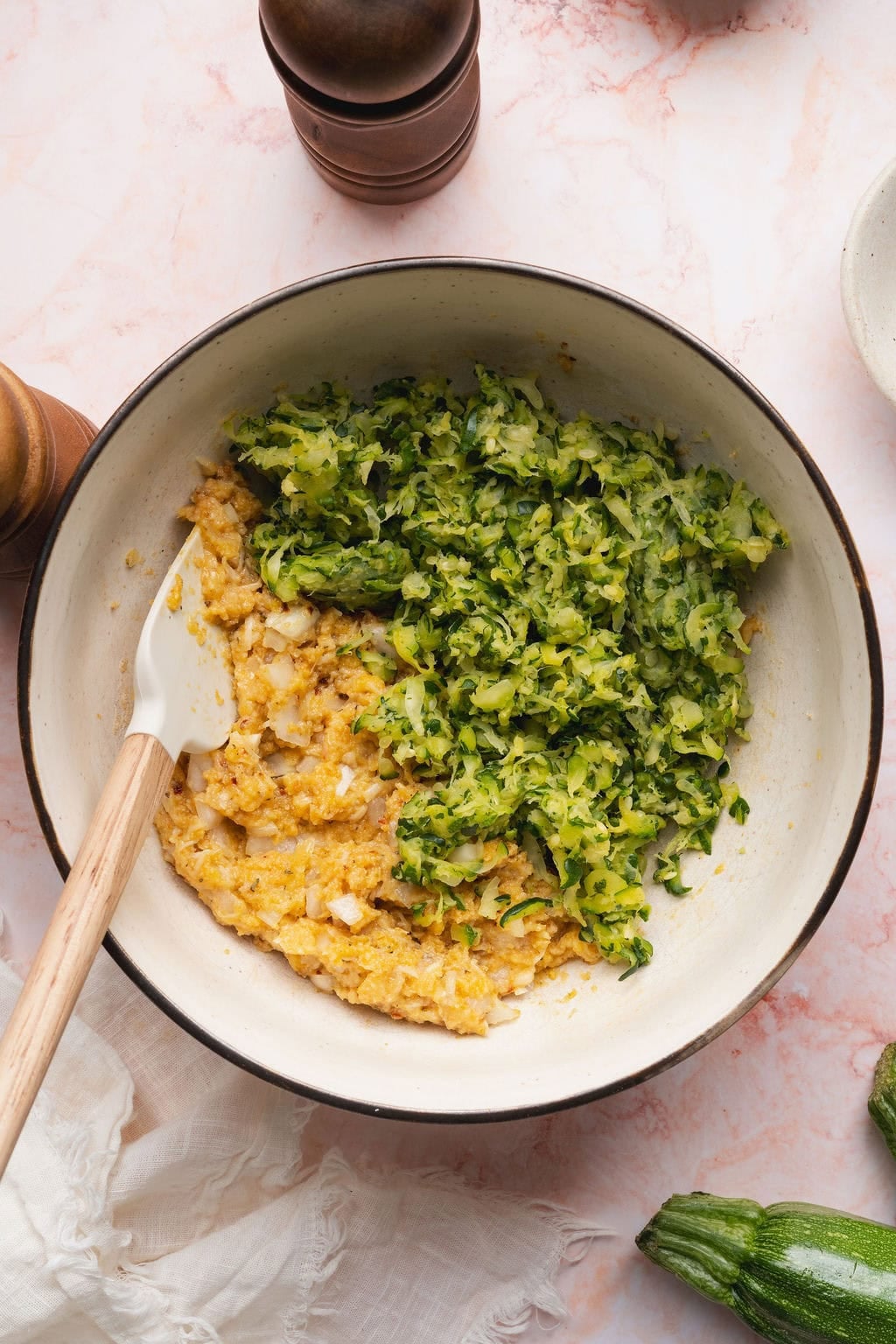 Shredded zucchini on top of mixed ingredients in a bowl
