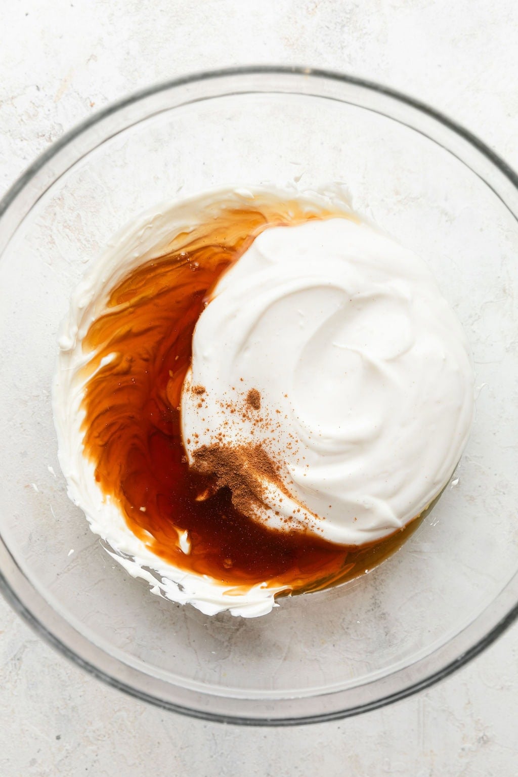 Overhead view of a glass bowl filled with fruit dip ingredients including vanilla ready to be mixed.