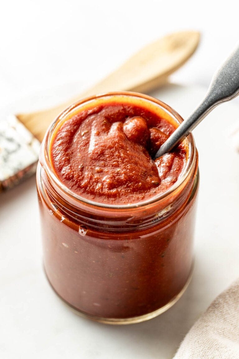 Overhead view of a glass jar filled with Homemade BBQ Sauce and a spoon in the jar.