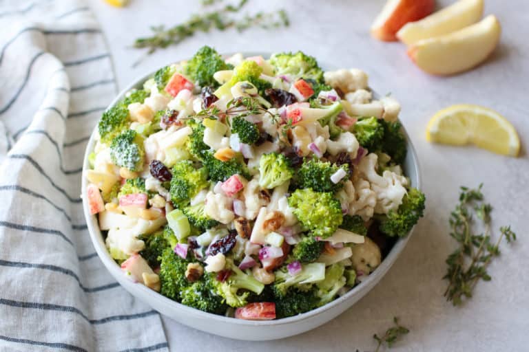 Apple broccoli cauliflower salad with raisins in white serving bowl