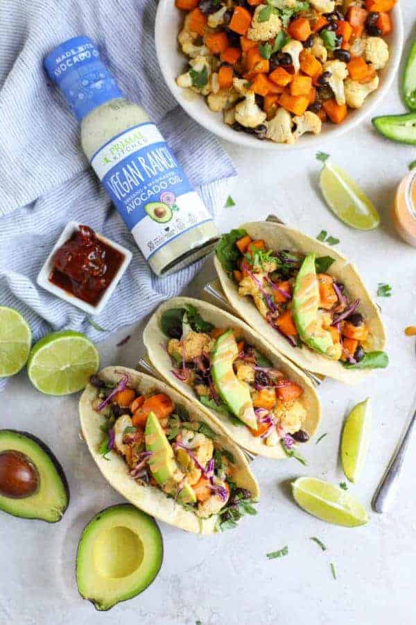 Overhead view of Vegan Cauliflower Sweet Potato Tacos with a bottle of Primal Kitchen Vegan Ranch lying next to them. 