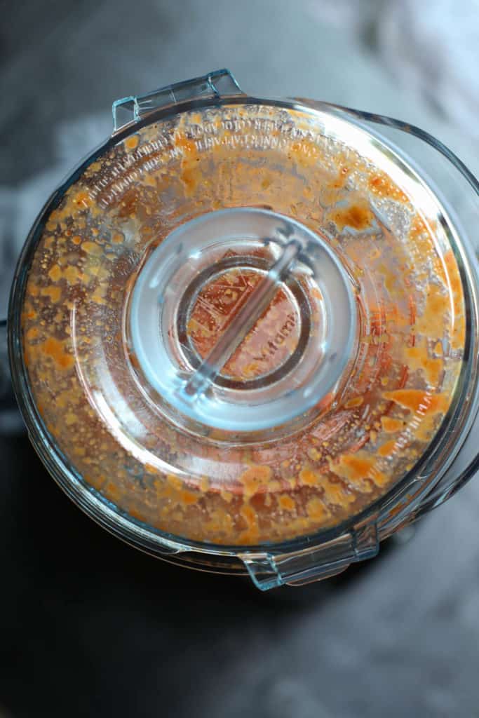 Overhead shot of lid on blender container with splatters of bbq sauce on the underside of the lid.