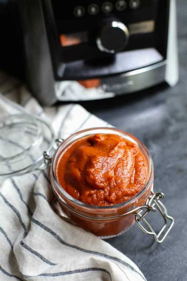 Jar of BBQ sauce with blender in the background. 