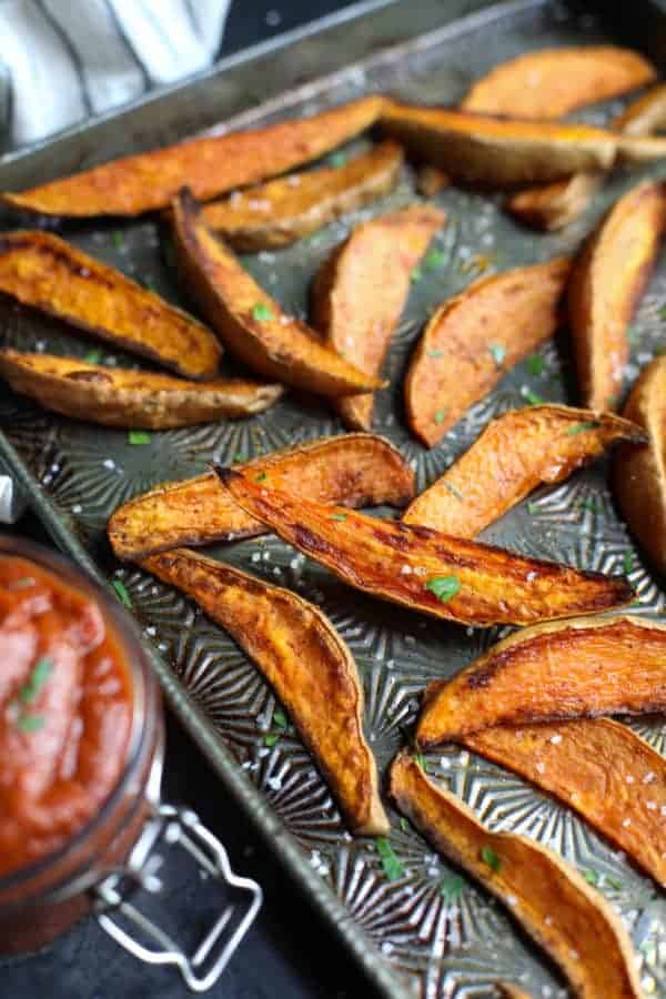 Vintage baking sheet with roasted sweet potatoes sprinkled with chopped parsley and coarse sea salt. 