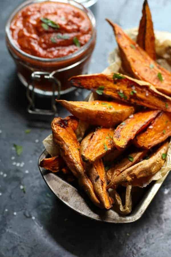 BBQ sauce with roasted sweet potato wedges on a table. 