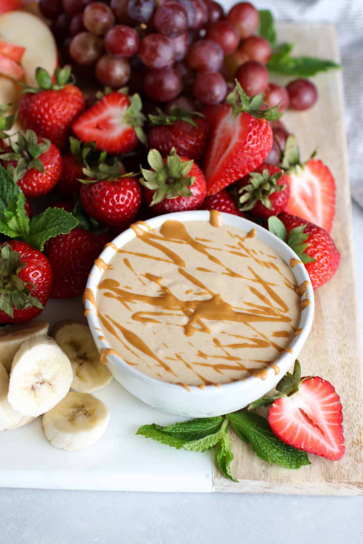 Easy Peanut Butter Yogurt Fruit Dip in a white bowl with fresh fruit around it 