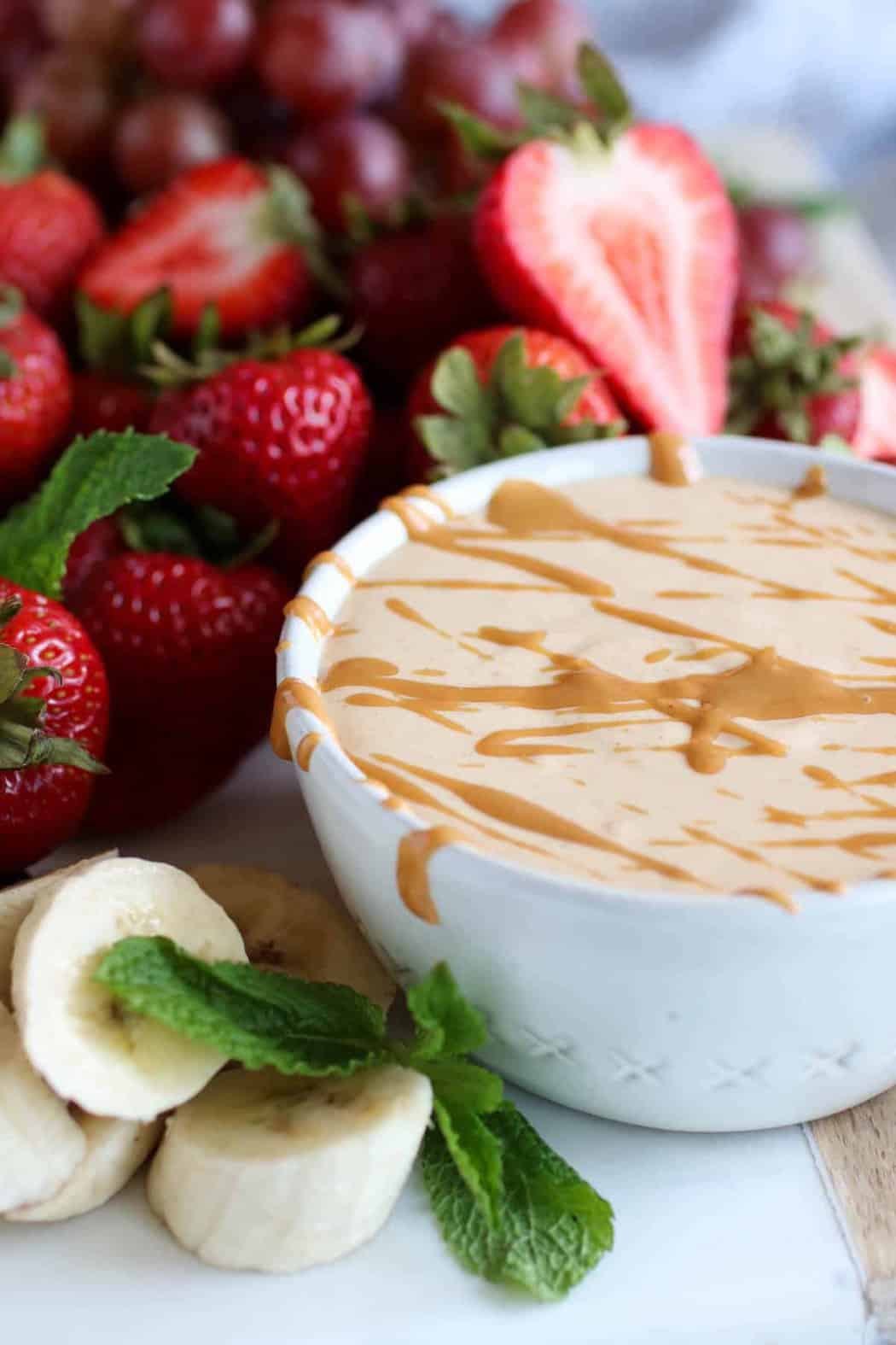 Easy Peanut Butter Yogurt Fruit Dip in a white bowl next to strawberries and banana slices