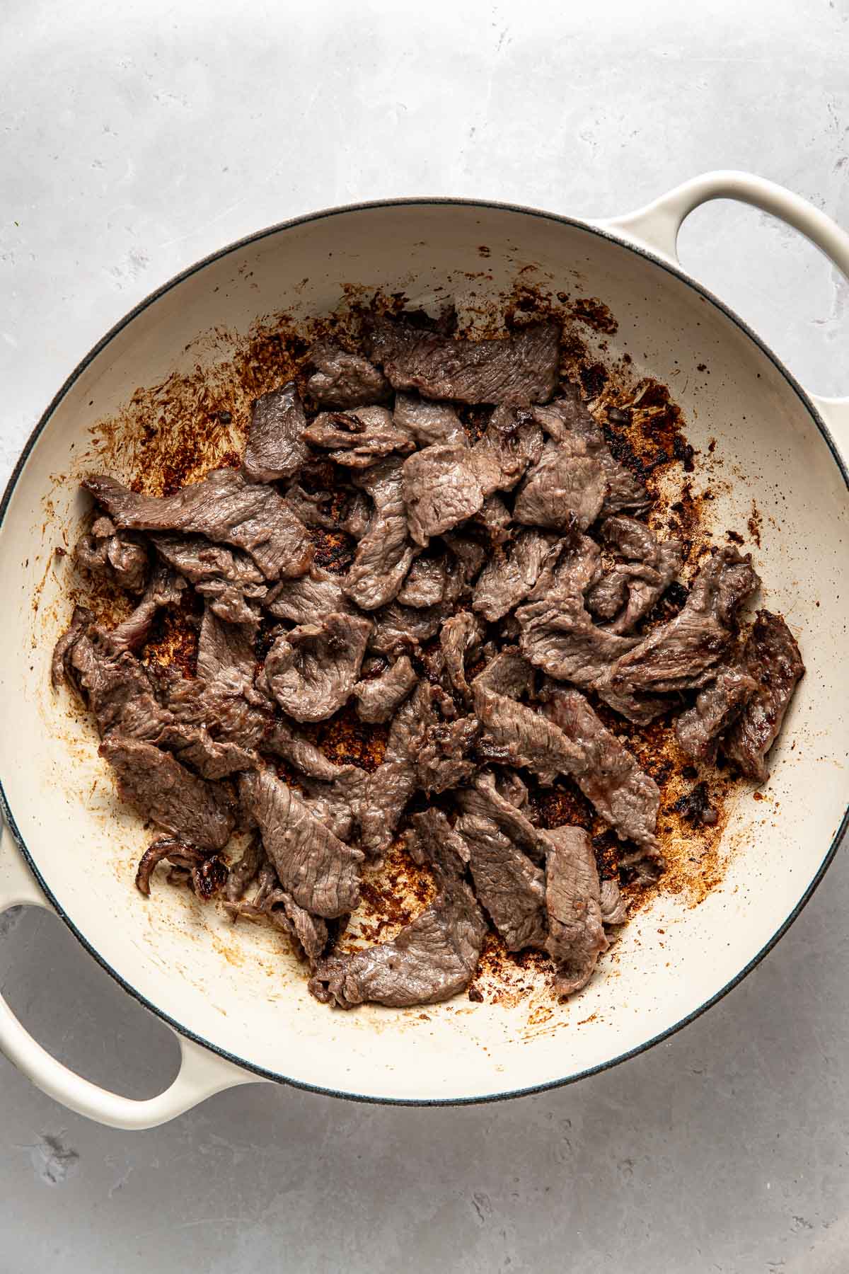 Overhead view of a skillet filled with freshly sauteed steak strips.