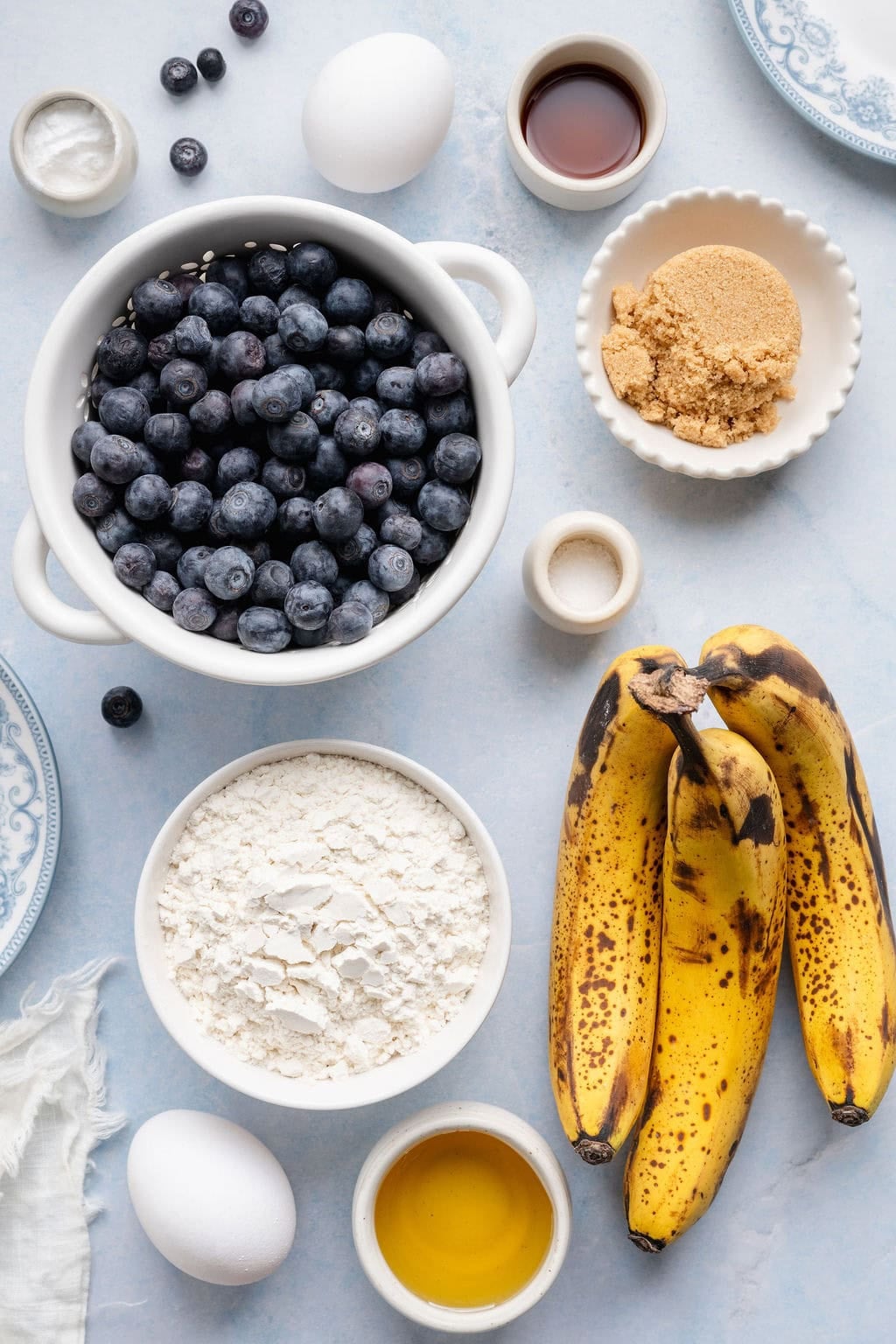 Overhead view of a variety of ingredient for Banana Blueberry Muffins in different sized bowls. 