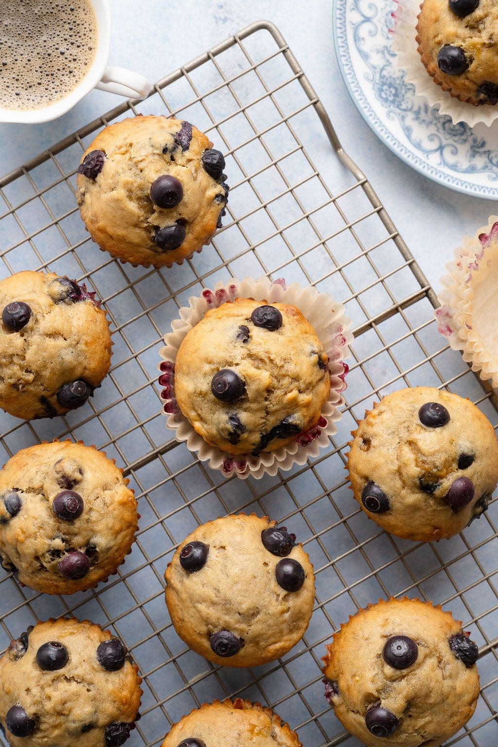Overhead view of several blueberry banana muffins on a wire cooling rack. 