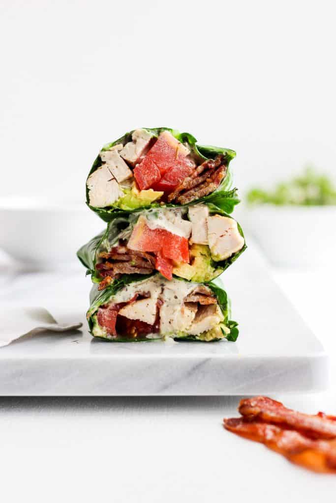 Chicken Bacon Club Collard Green Wraps stacked into threes on a white board