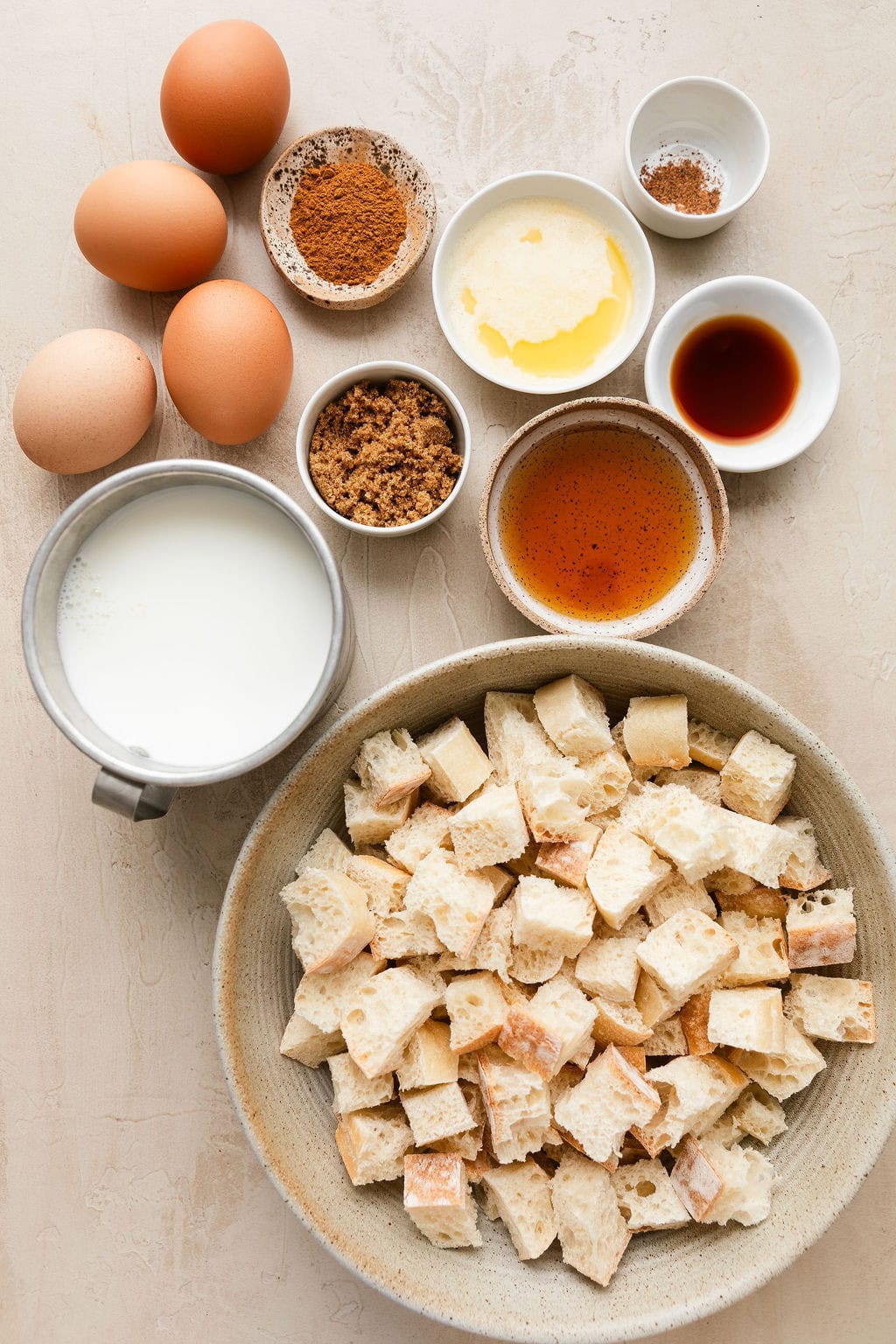 Overhead view of a variety of ingredients for French Toast Casserole in different sized bowls. 