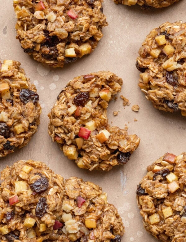 Overhead view oatmeal cookies with apple chunks on a counter with a bite taken from one cookie