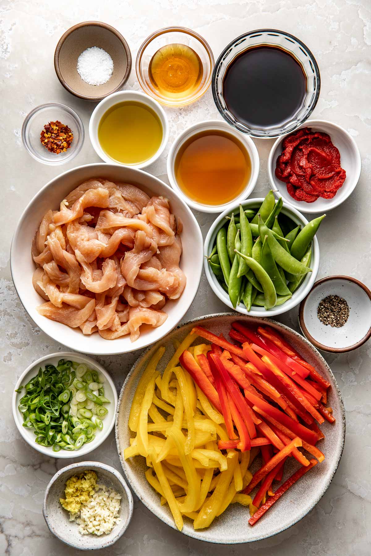 Overhead view of a variety of ingredients for Chicken Stir Fry in different sized bowls.