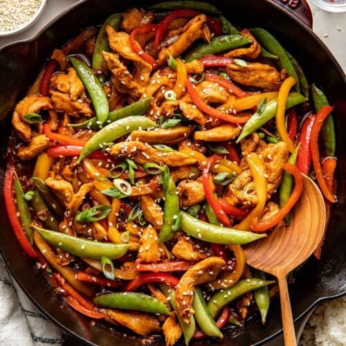 Overhead view of a colorful skillet of Chicken Stir Fry topped with sesame seeds.