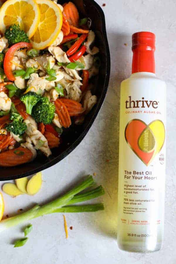 Overhead view of Thrive Culinary Algae Oil next to a pan of ingredients for Orange-Ginger Chicken Stir Fry