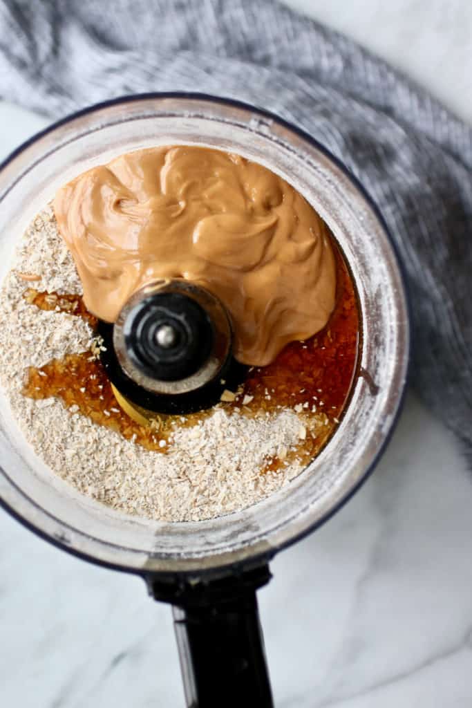 Processed oats, honey and drippy peanut butter in food processor bowl