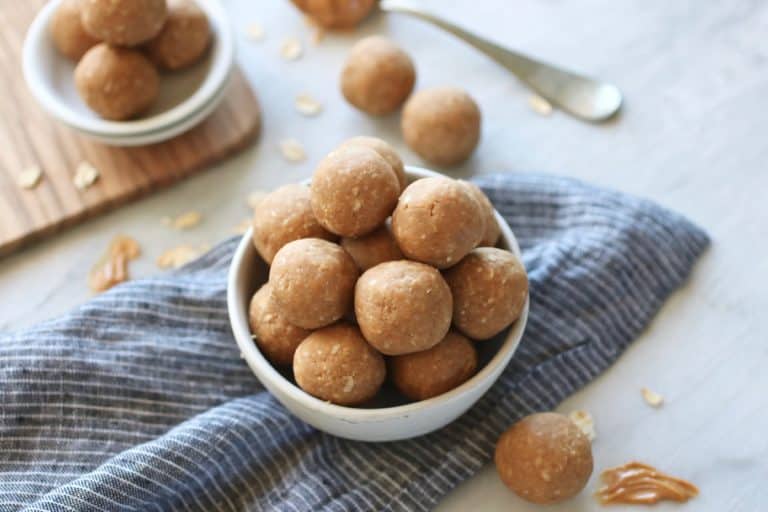 3-Ingredient Peanut butter energy balls piled up high in white bowl.