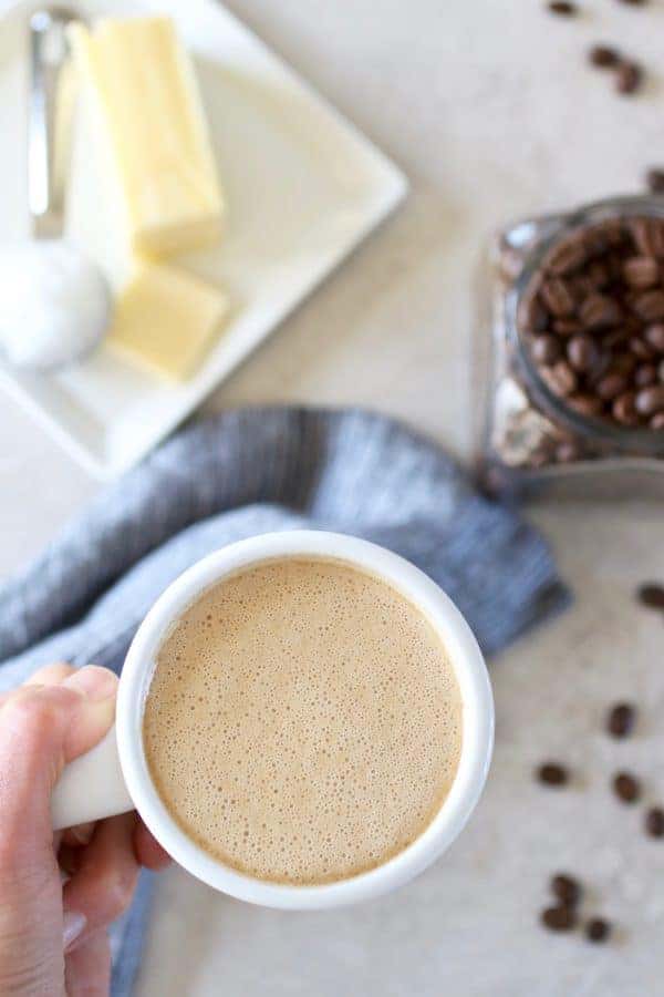 Overhead view of a cup of Keto Coffee lifted towards the camera