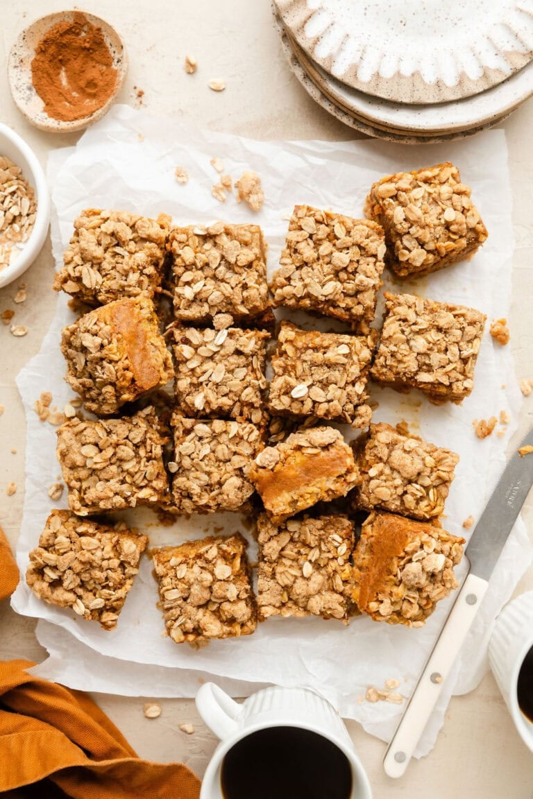 Overhead view of a batch of freshly baked Pumpkin Pie Bars cut into squares on parchment paper.