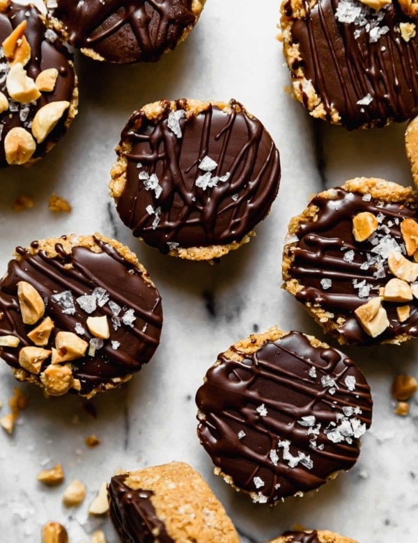 Overhead view peanut butter bites topped with chocolate, crushed peanuts and sea salt on a counter