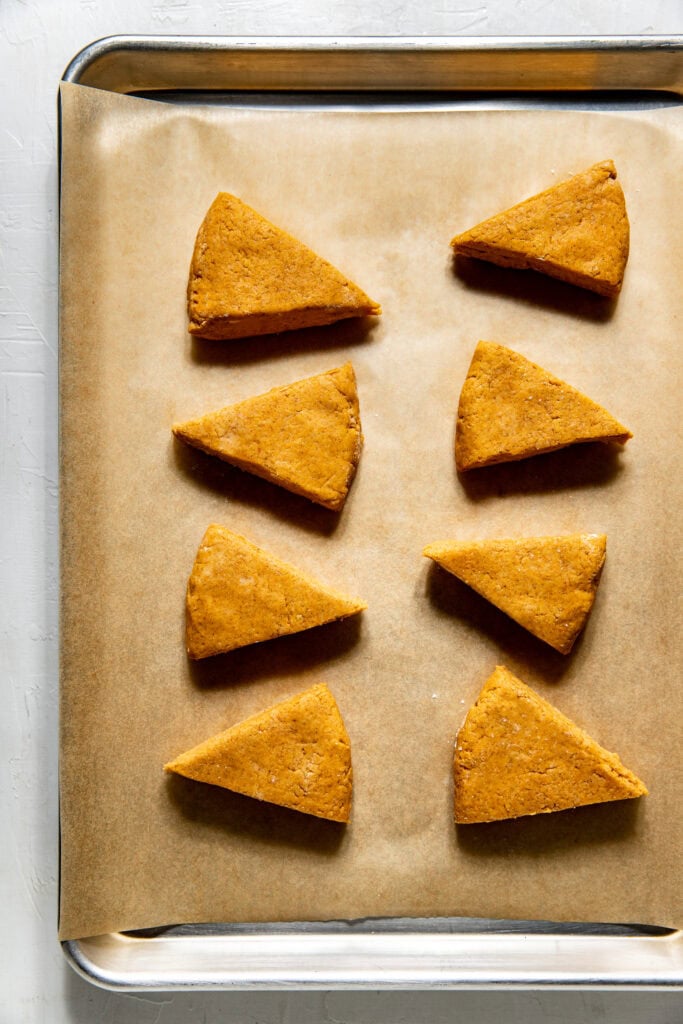 Overhead view of cut pieces of Gluten-Free Pumpkin Spice Scones dough ready for baking. 