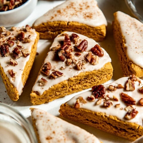 Gluten-Free Pumpkin Spice Scones topped with icing and crushed pecans on a tray