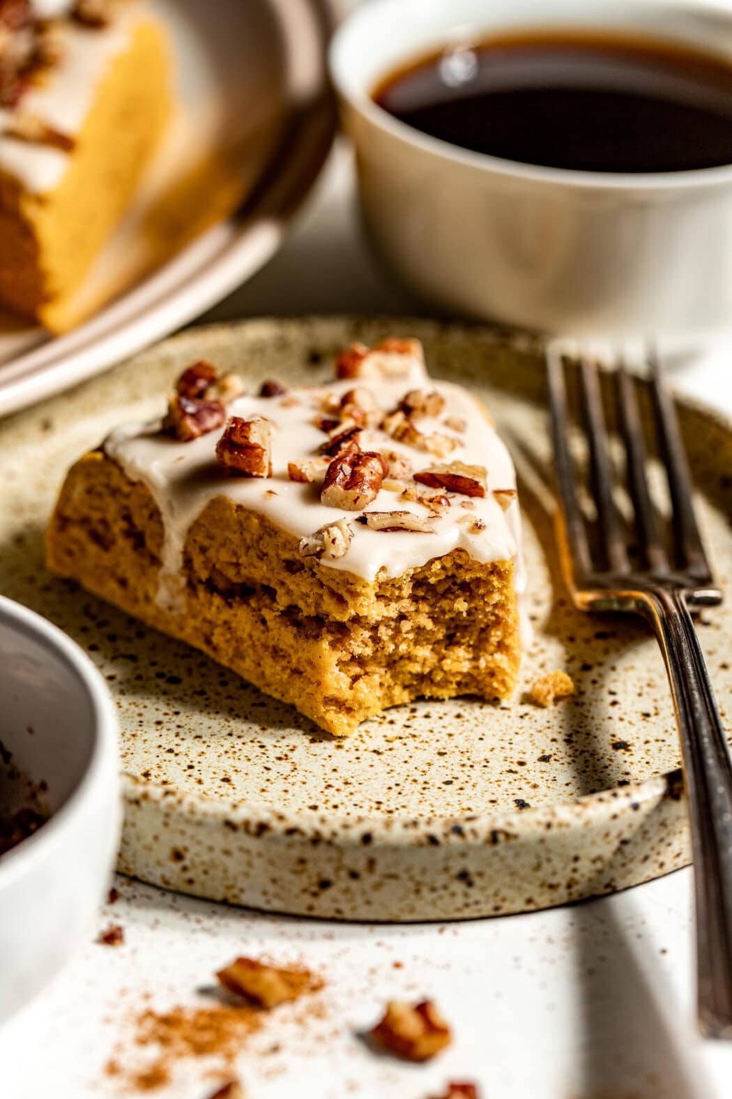 Close up view of a piece of a Gluten-Free Pumpkin Spice Scone next to a cup of coffee. 