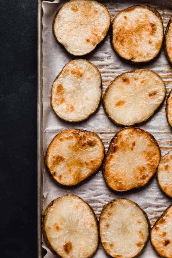 Overhead view of sliced sweet potatoes browned in an oven on a baking sheet