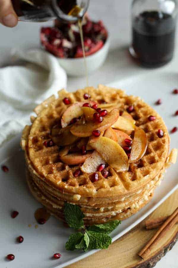 Overhead view of syrup being poured on a stack of waffles