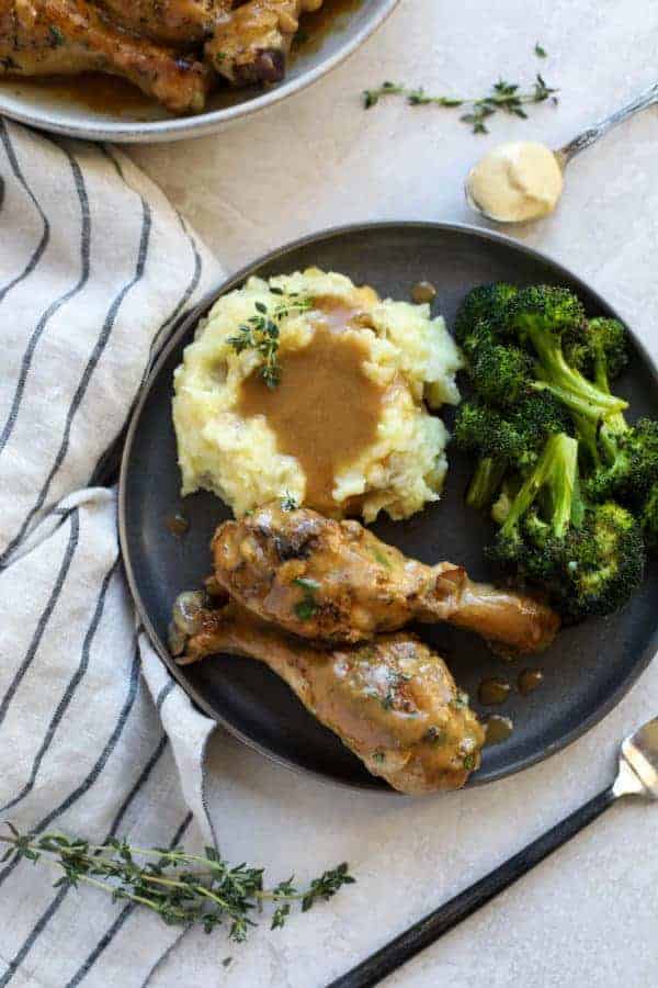 Overhead view of two chicken legs on a plate with mashed potatoes & gravy, and broccoli 